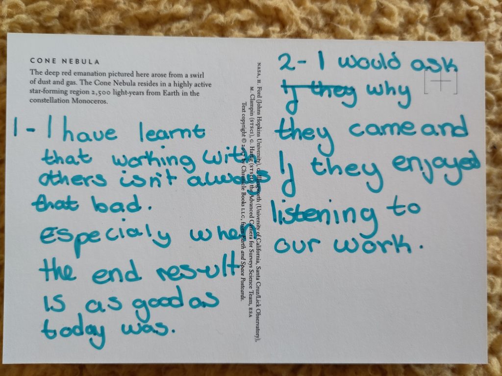 The image shows the back of a postcard with blue writing. The text reads "1 - I have learnt that working with others isn't always that bad. Especially when the end result is as good as today was. 2 - I would ask why they came and if they enjoyed listening to our work."